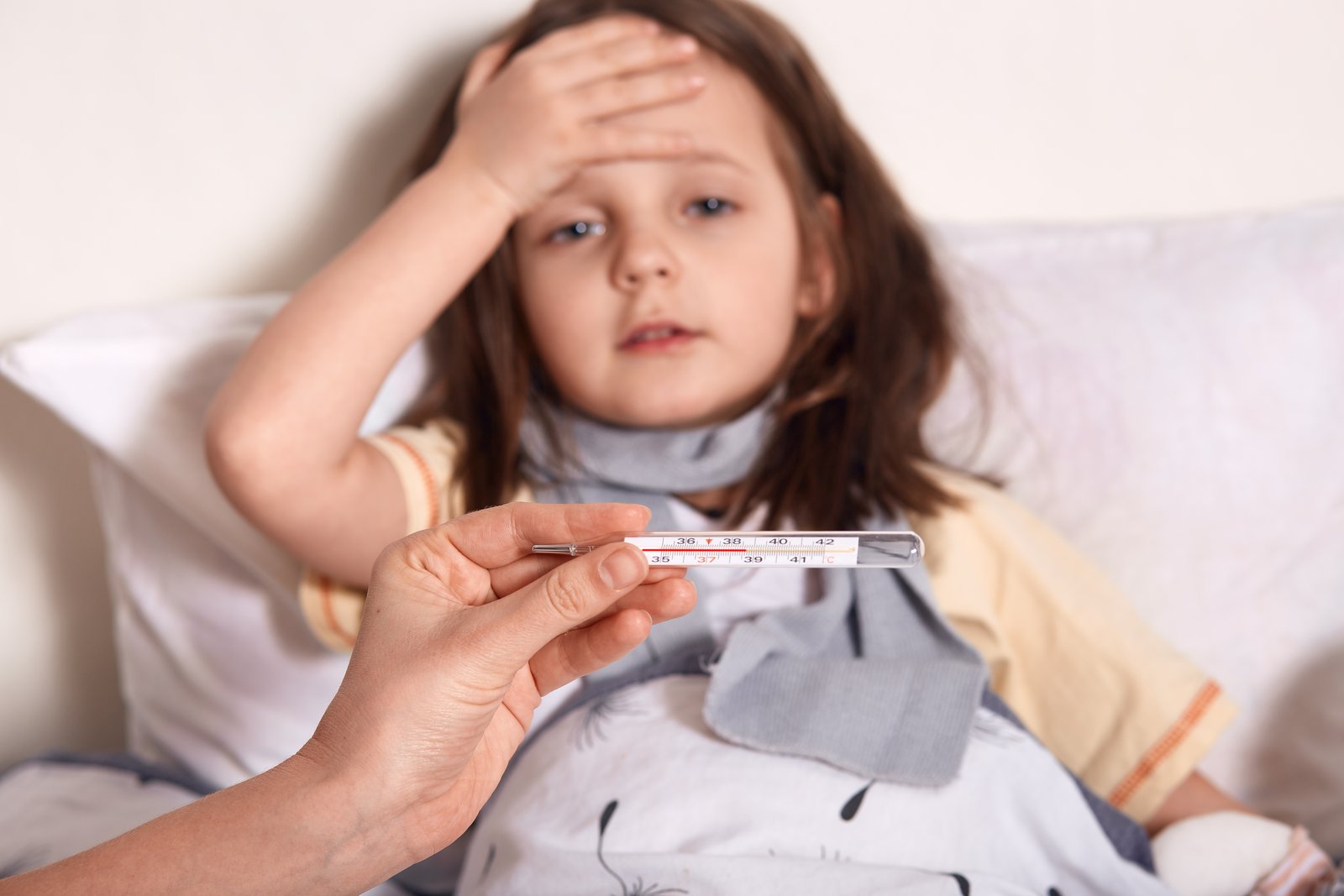 Parent checking a child's body temperature with a digital thermometer to identify fever in children