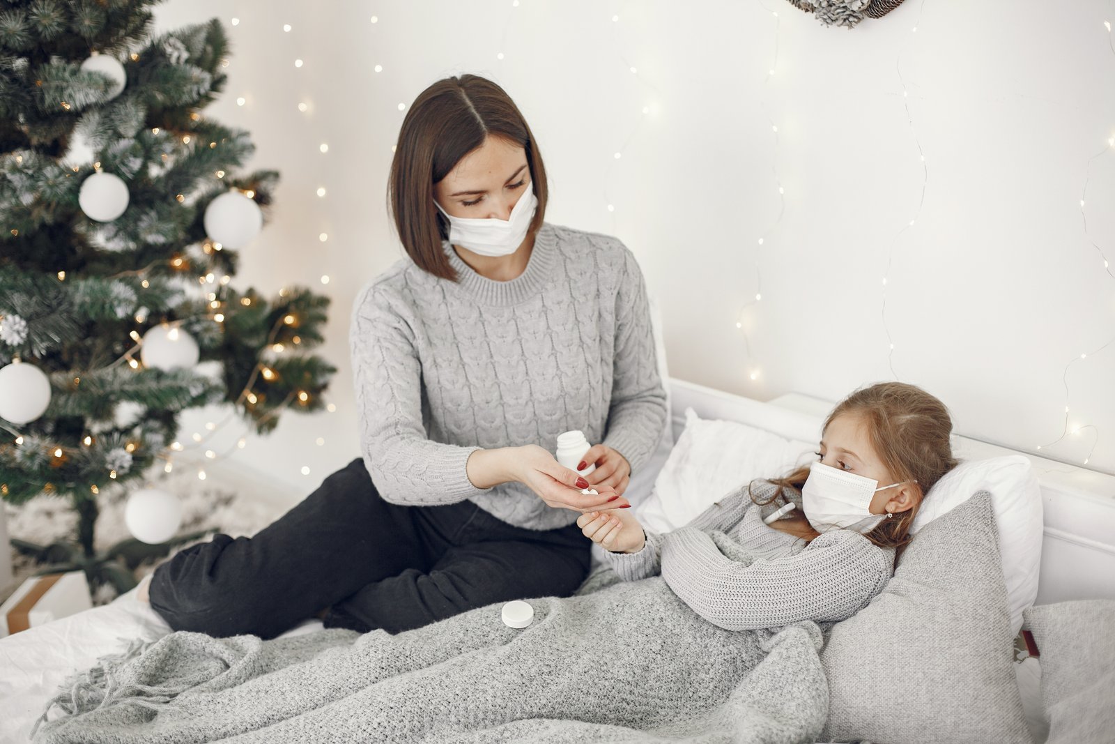 Mother caring for a child with fever at home by checking temperature and encouraging fluids
